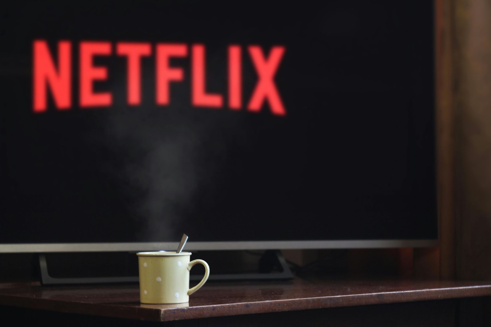 The Netflix logo on a TV screen with a steaming mug in front of it