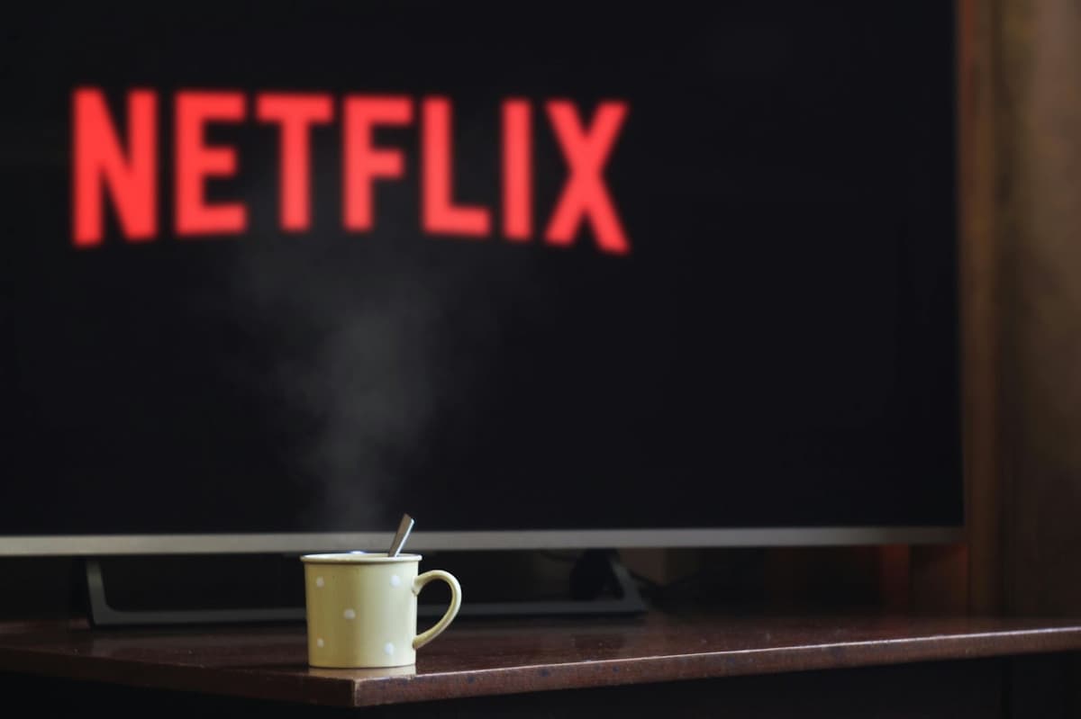 The Netflix logo on a TV screen with a steaming mug in front of it